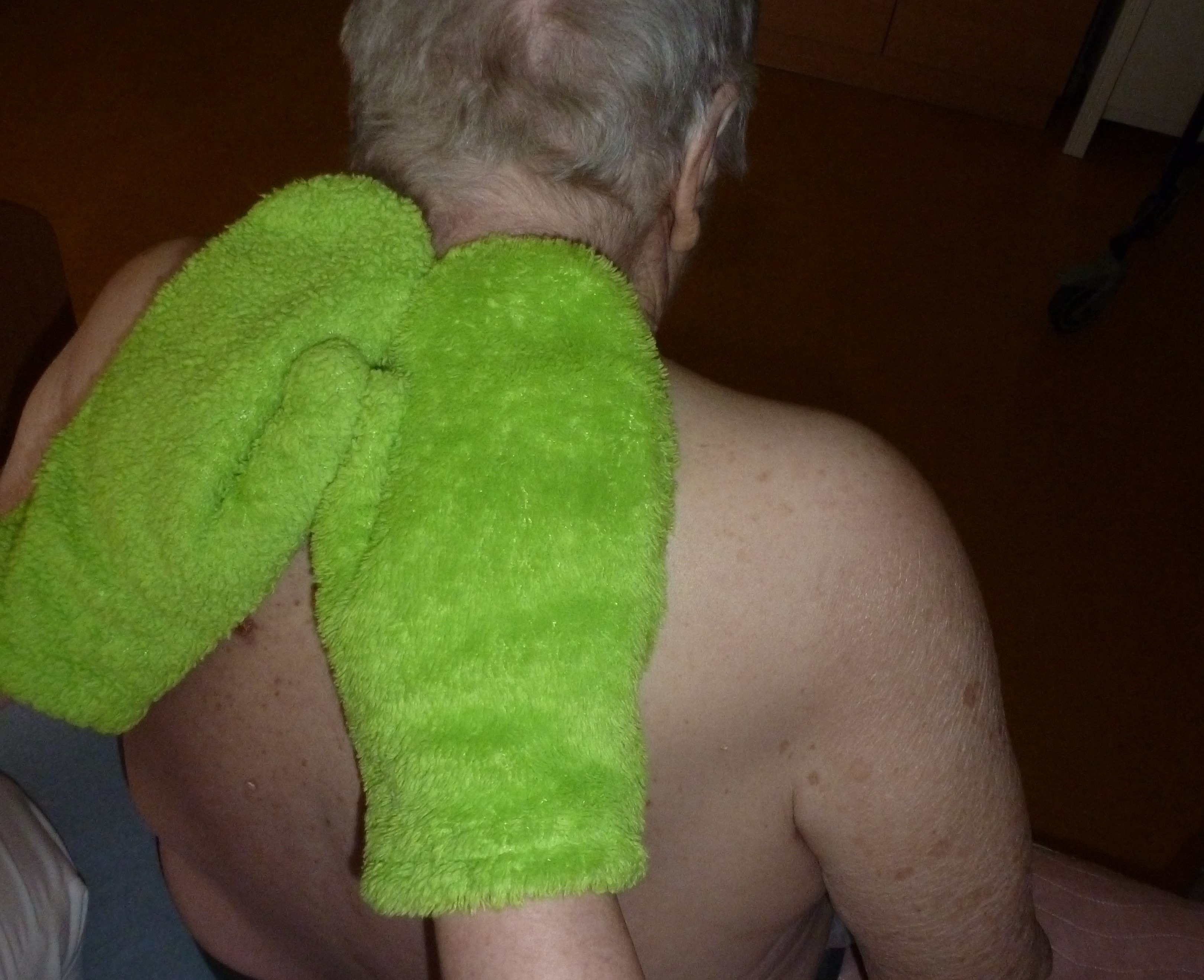 Pečovatelka přovádí klientovi bazální stimulaci pomocí forté rukavic